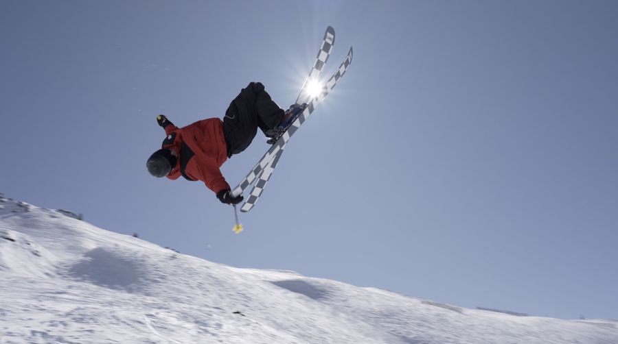 A skier inverted against the sun on checkered skis