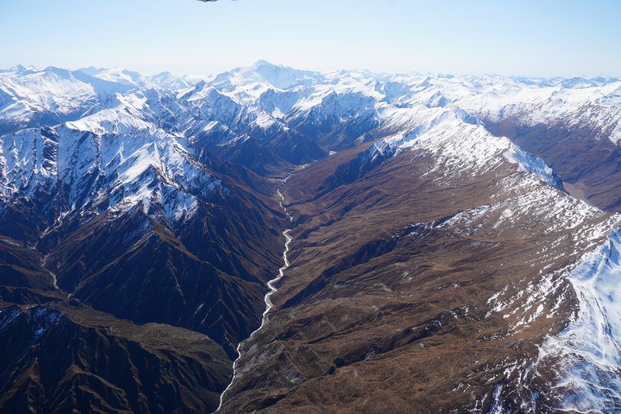 Aerial view of a braided river winding through snowy mountains