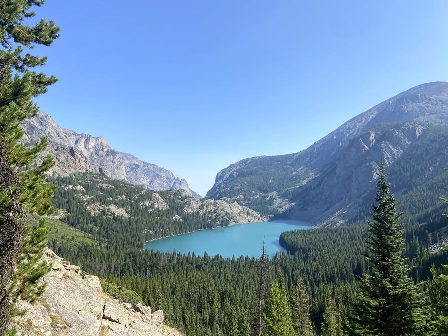 A turquoise alpine lake in a forested granite valley