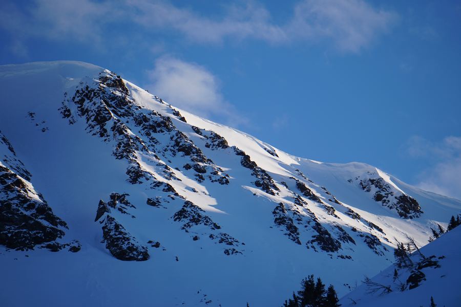 Wind-sculpted snow and rock bands glowing in low sun