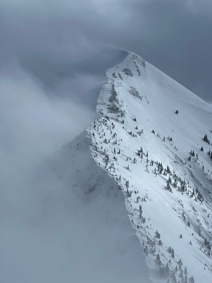 A corniced ridgeline disappearing into storm clouds